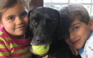Rosie, a black rescue dog, with the two children in her family